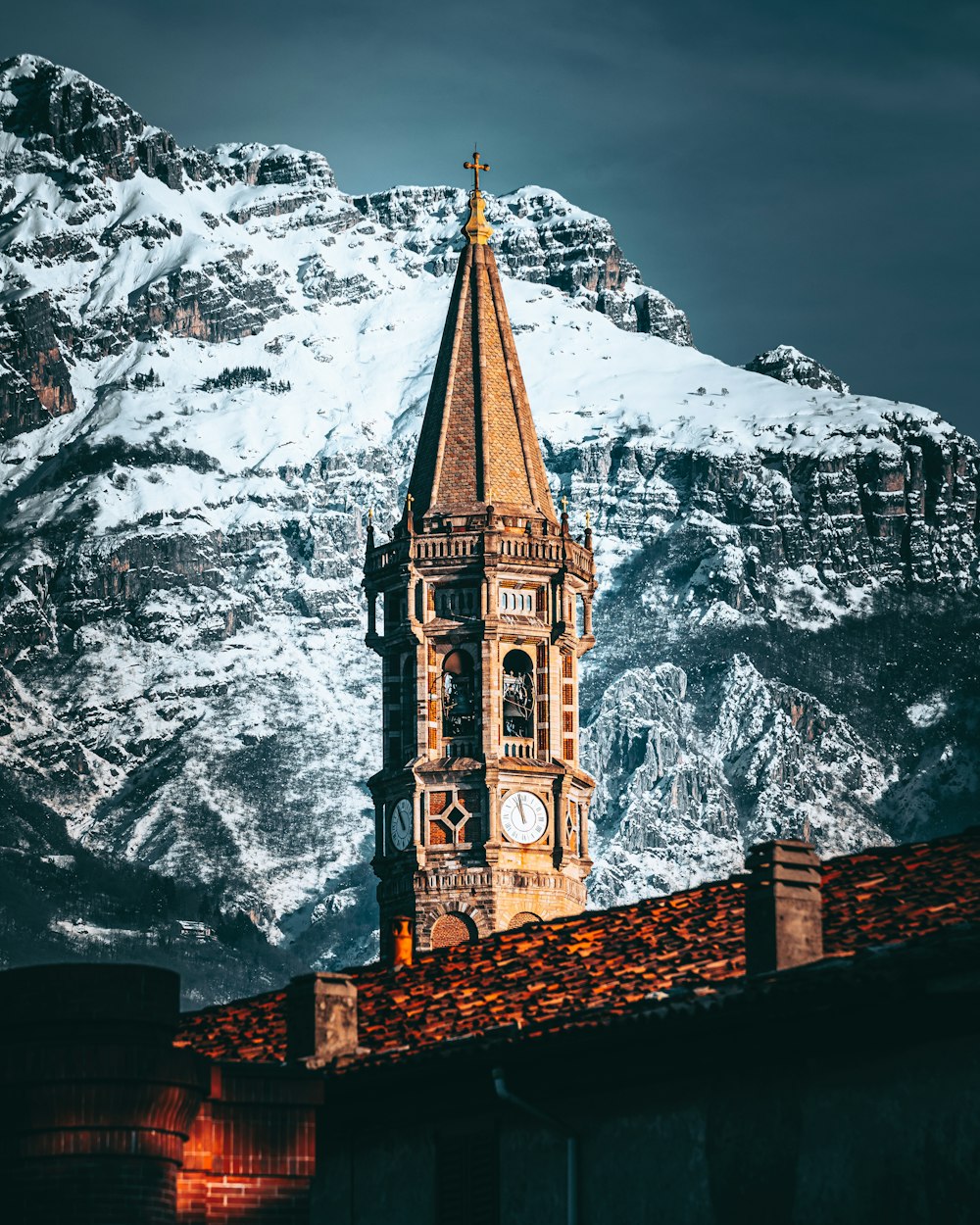Una torre dell'orologio in cima a un edificio con una montagna sullo sfondo