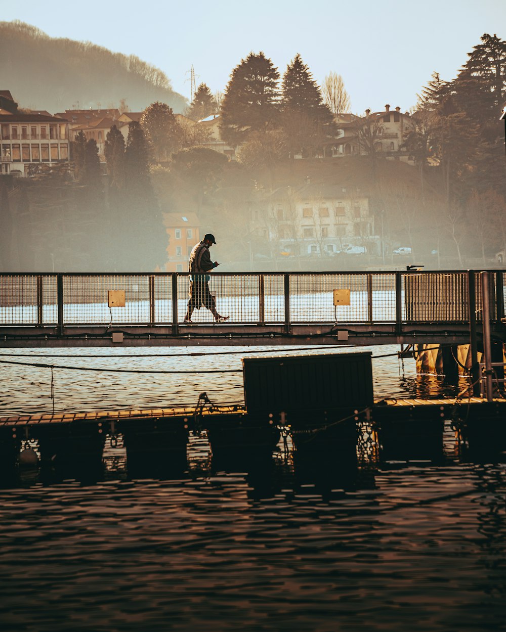 a man walking across a bridge over a body of water