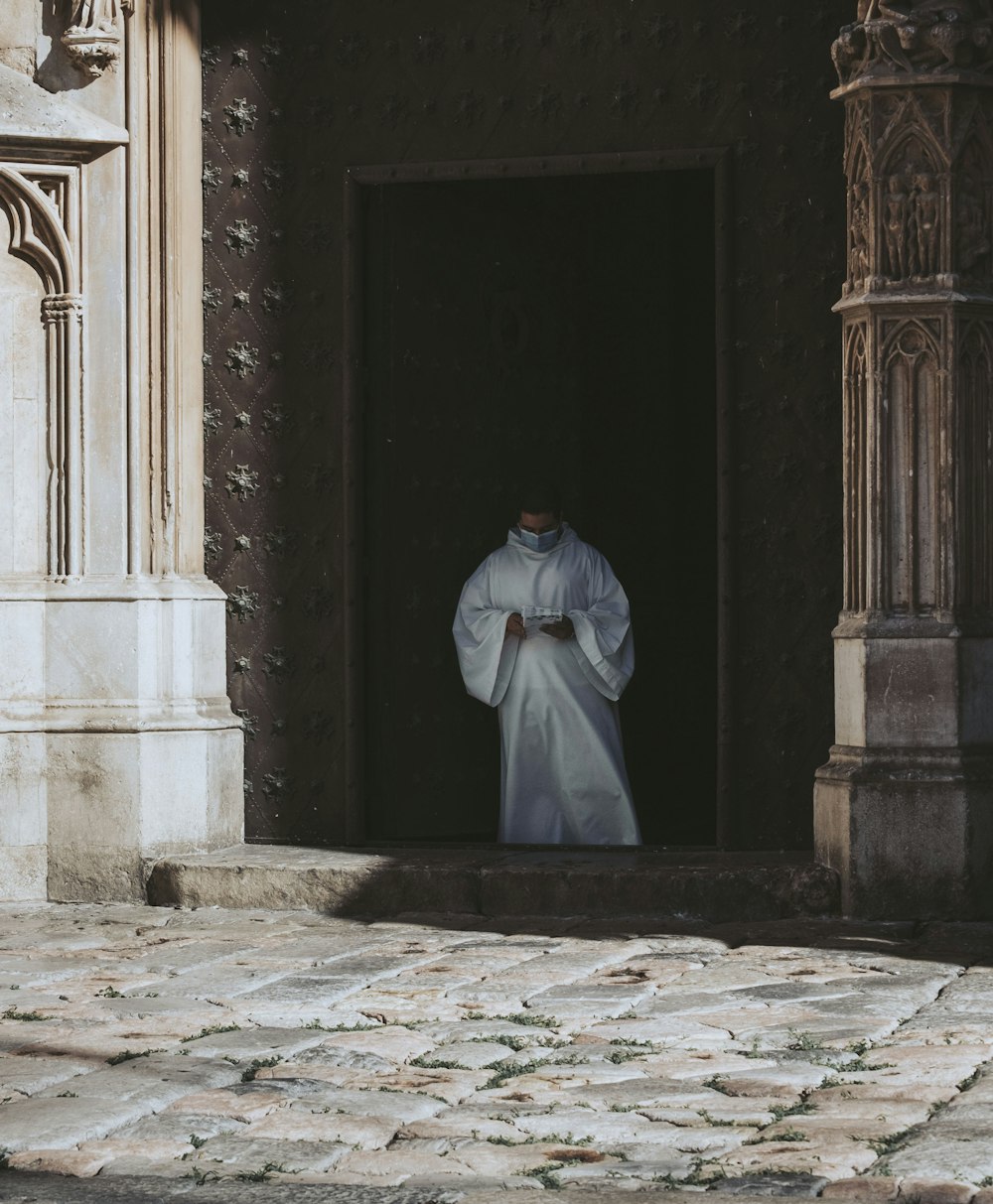 a man in a white robe standing in a doorway