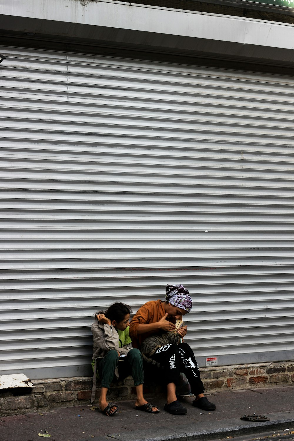 two people sitting on a bench in front of a building