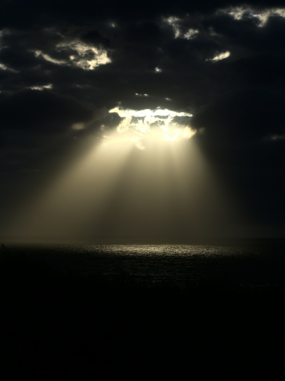 太陽が海の上の雲を通して輝いています