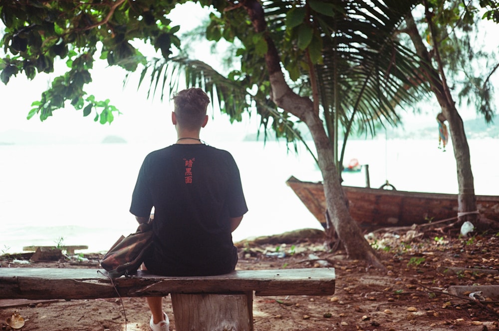 a man sitting on a bench looking out at the water