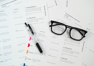 a pair of glasses sitting on top of a pile of paper