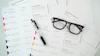 a pair of glasses sitting on top of a pile of paper