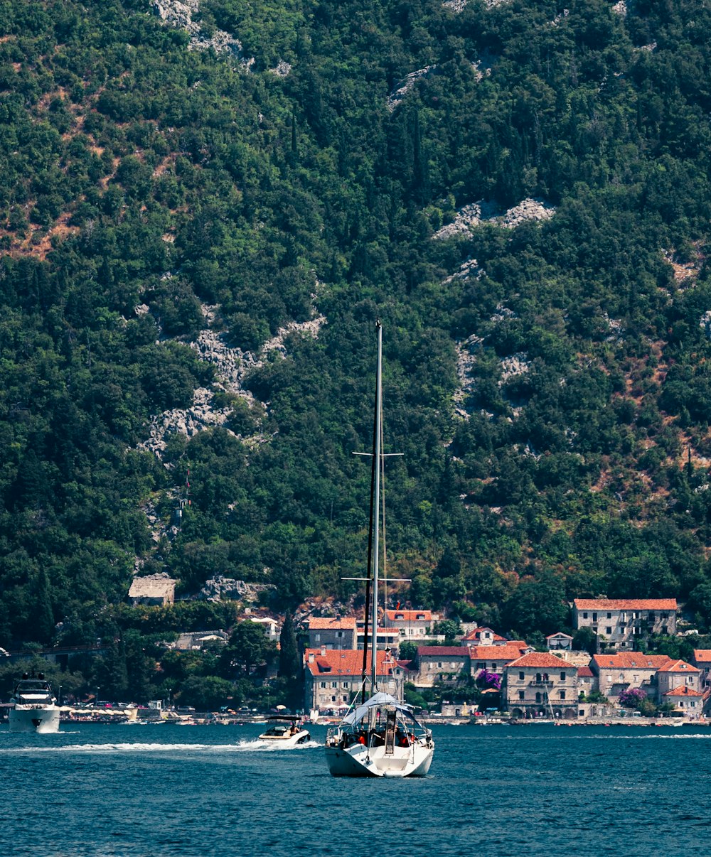 una barca a vela in uno specchio d'acqua vicino a una collina