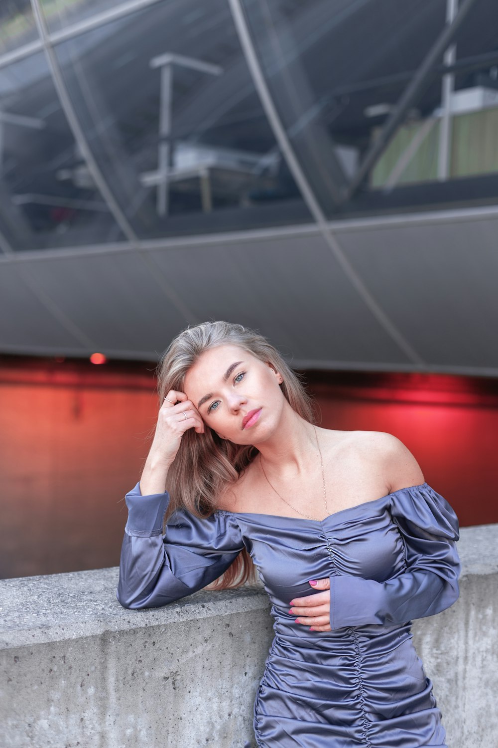 Une femme en robe bleue appuyée contre un mur