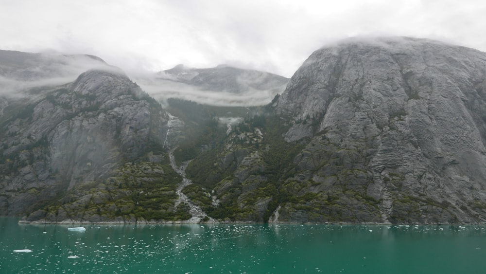 a body of water surrounded by mountains under a cloudy sky