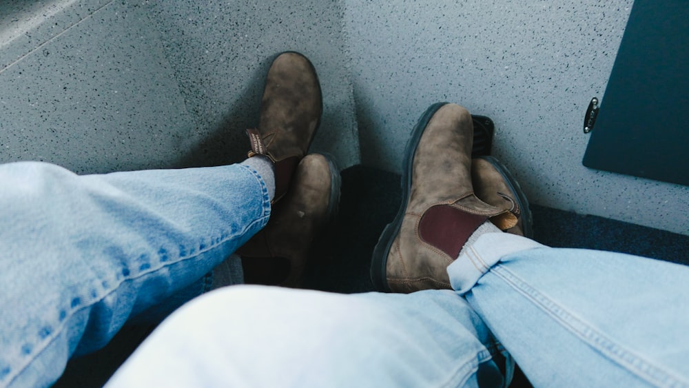 a pair of feet in jeans and brown shoes
