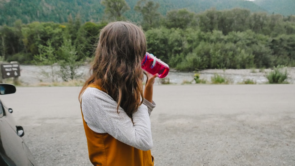 a woman standing next to a car holding a red cup