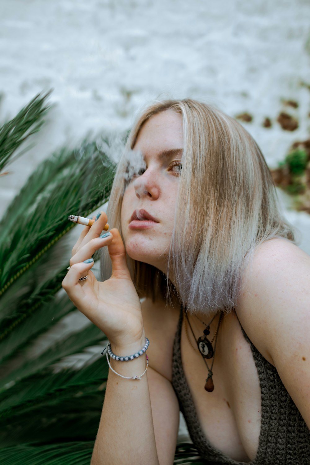 a woman smoking a cigarette next to a palm tree