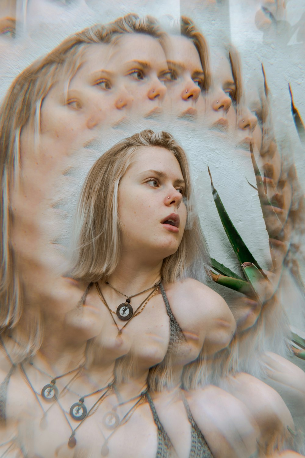 a woman standing in front of a mirror holding a plant