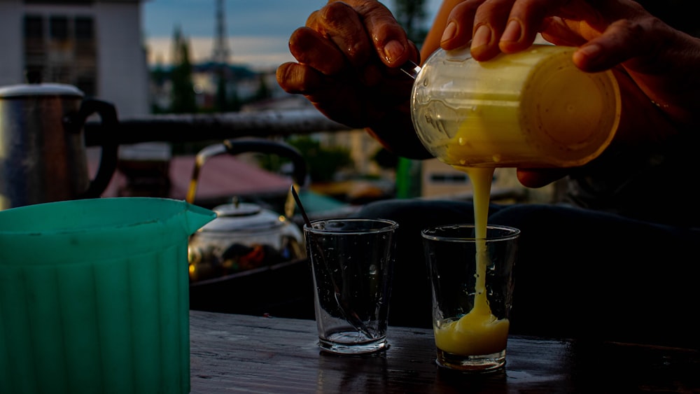 a person pouring a drink into two glasses