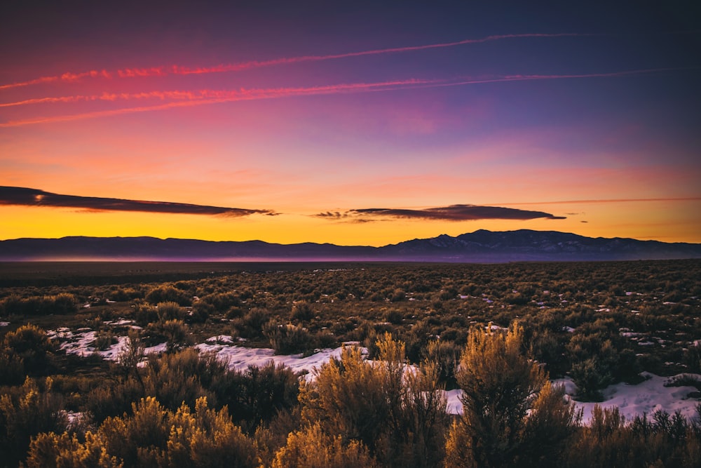 the sun is setting over the mountains in the desert