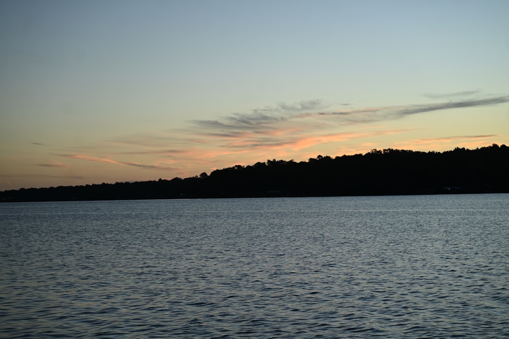 a body of water with a hill in the background