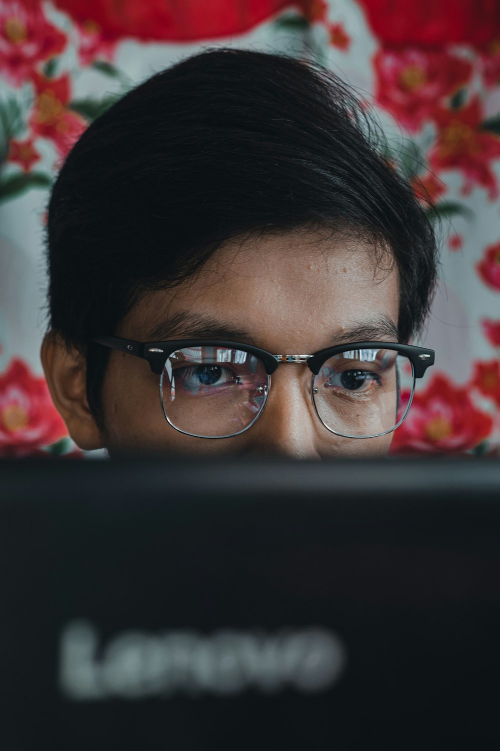 a person wearing glasses looking at a laptop