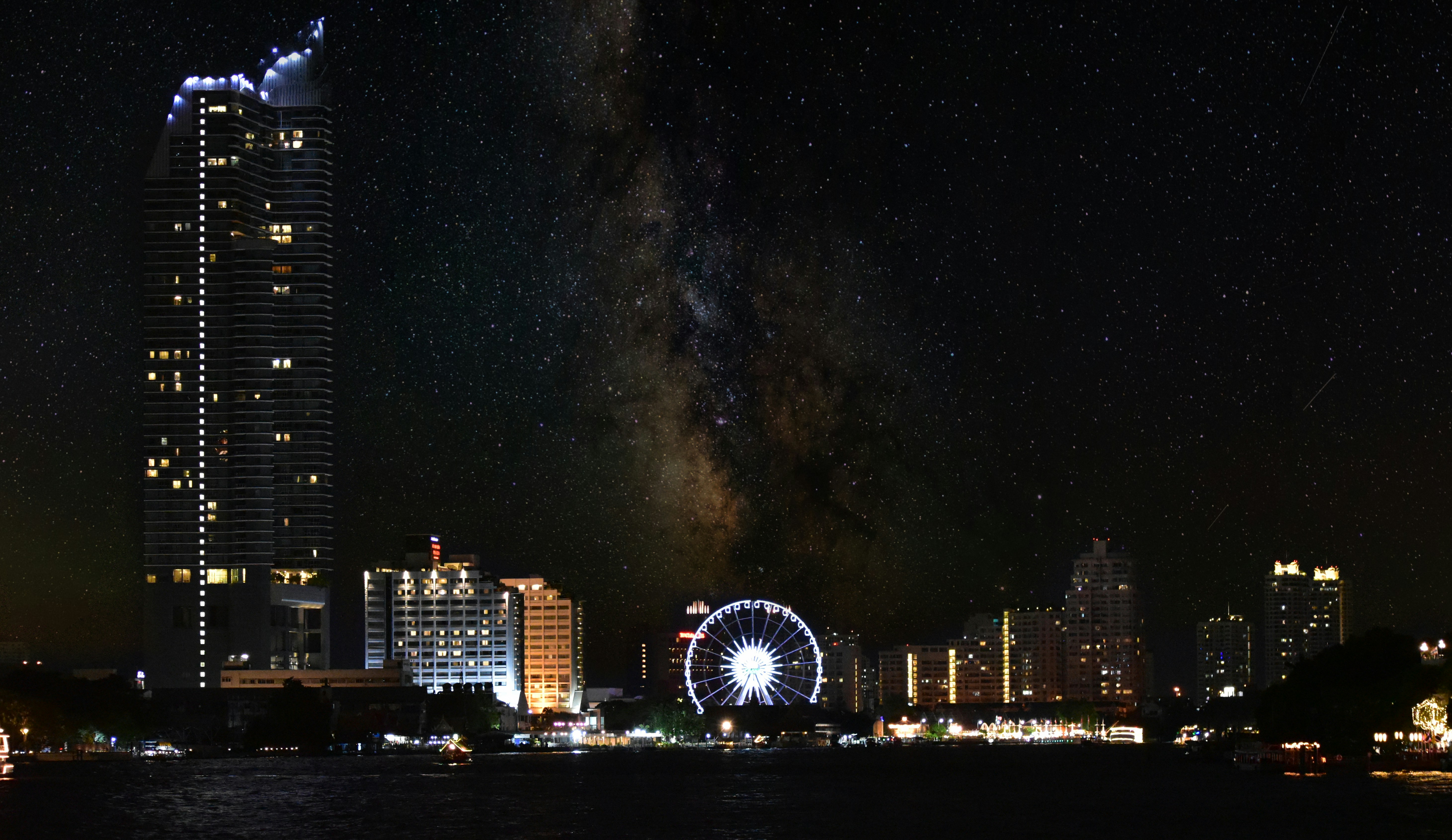 a night view of a city with a ferris wheel in the foreground