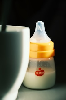 a baby bottle sitting next to a cup