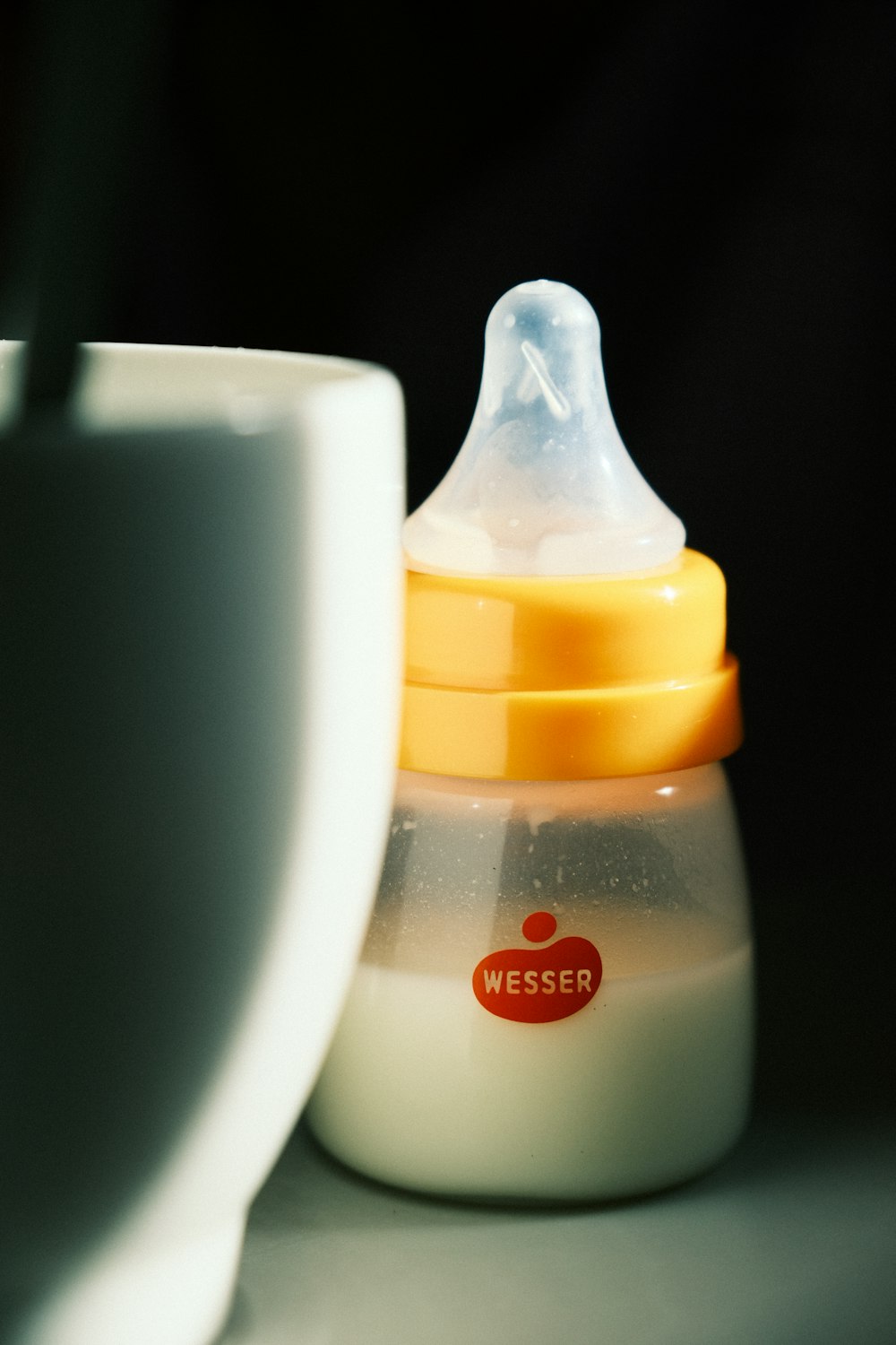 a baby bottle sitting next to a cup