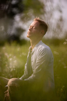a man sitting in a field of tall grass