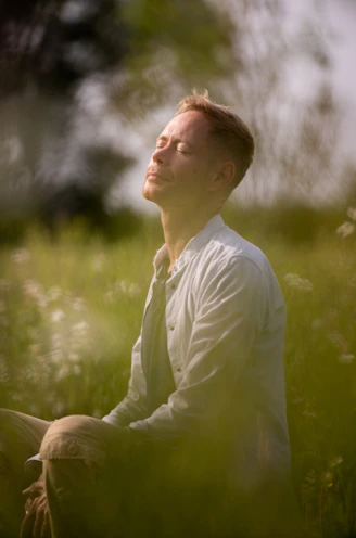 a man sitting in a field of tall grass
