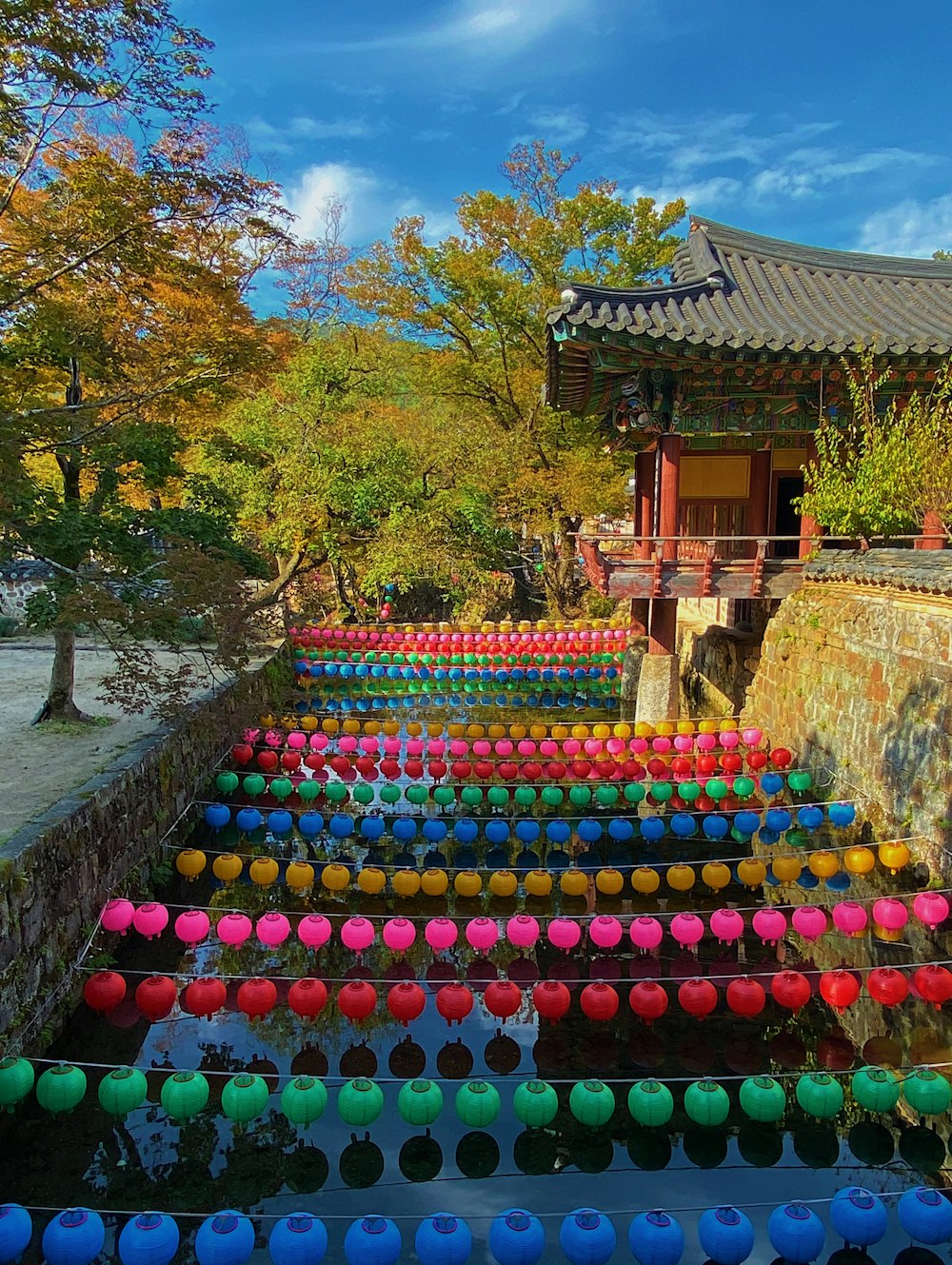 a bunch of colorful cups sitting on top of a stone wall