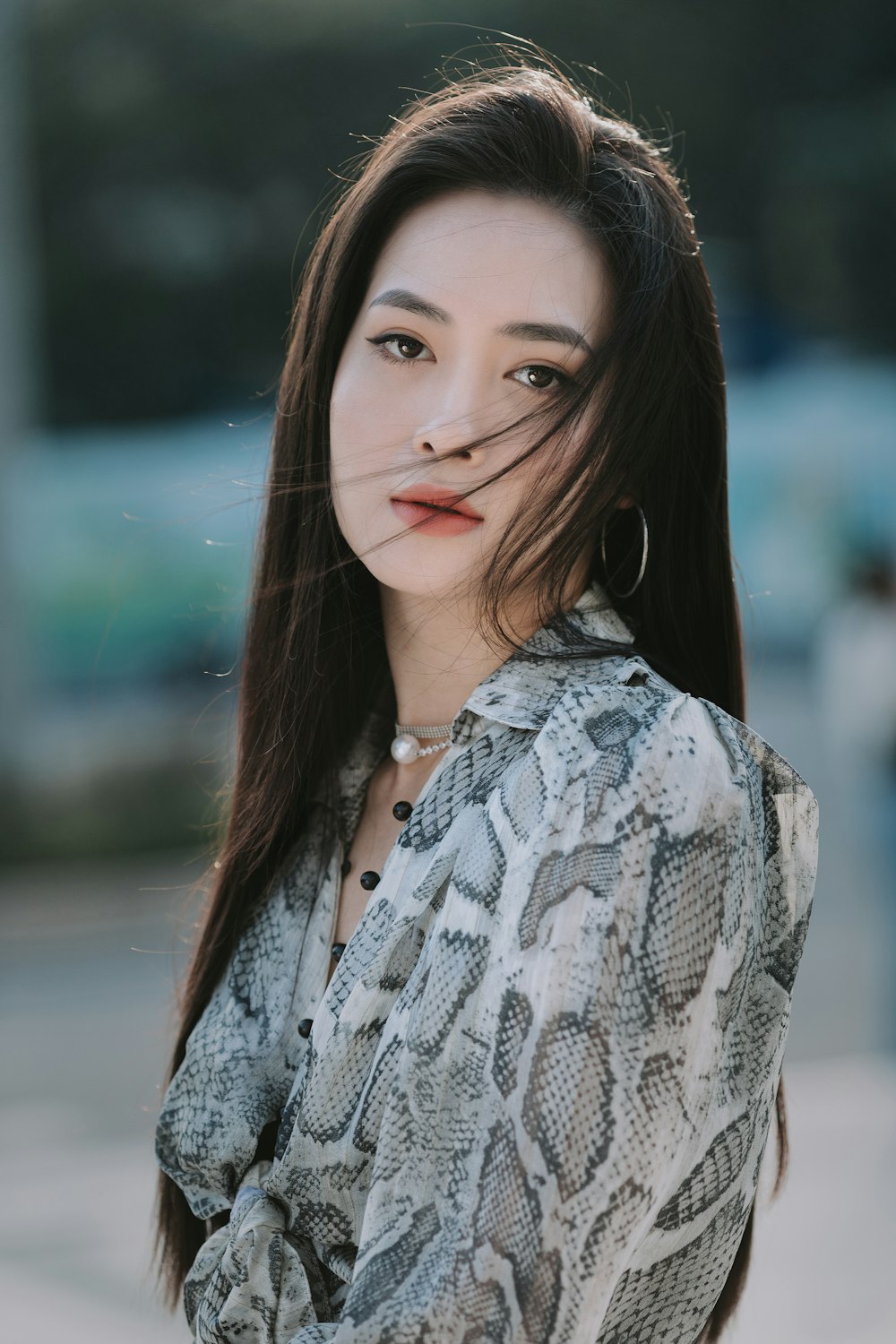 a woman with long hair wearing a snake skin shirt