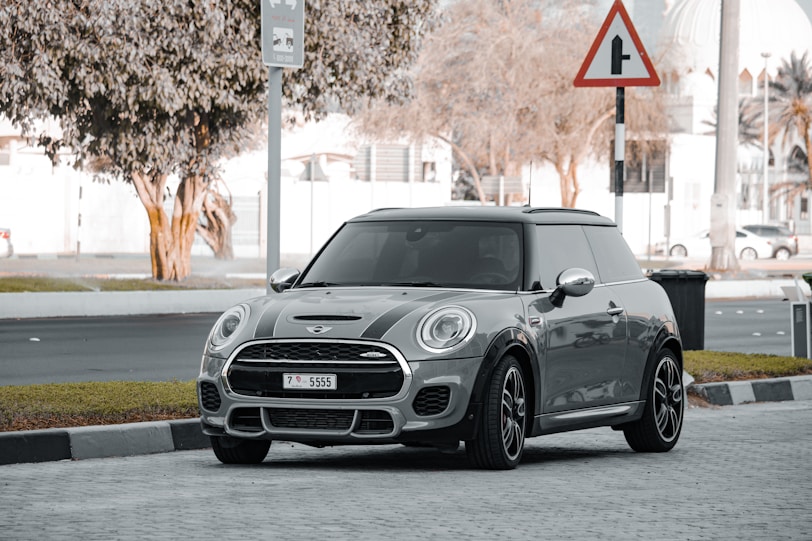 a grey mini cooper parked on the side of the road