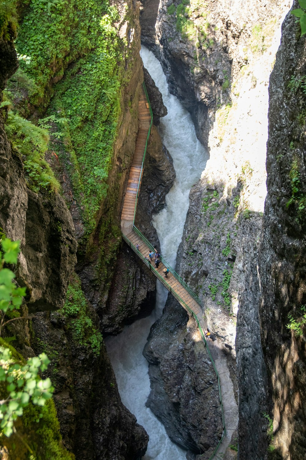a long wooden bridge over a river in a canyon