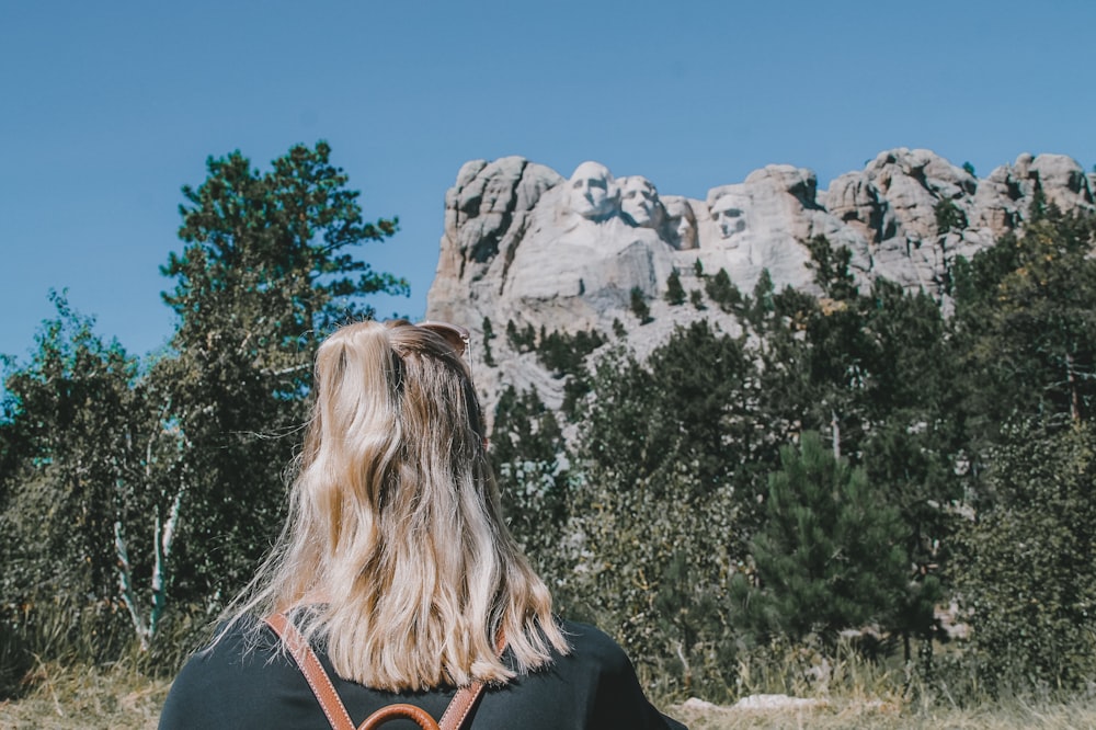 a woman with a backpack standing in front of a mountain