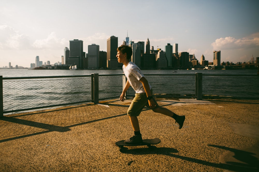 a man riding a skateboard down a sidewalk next to a body of water