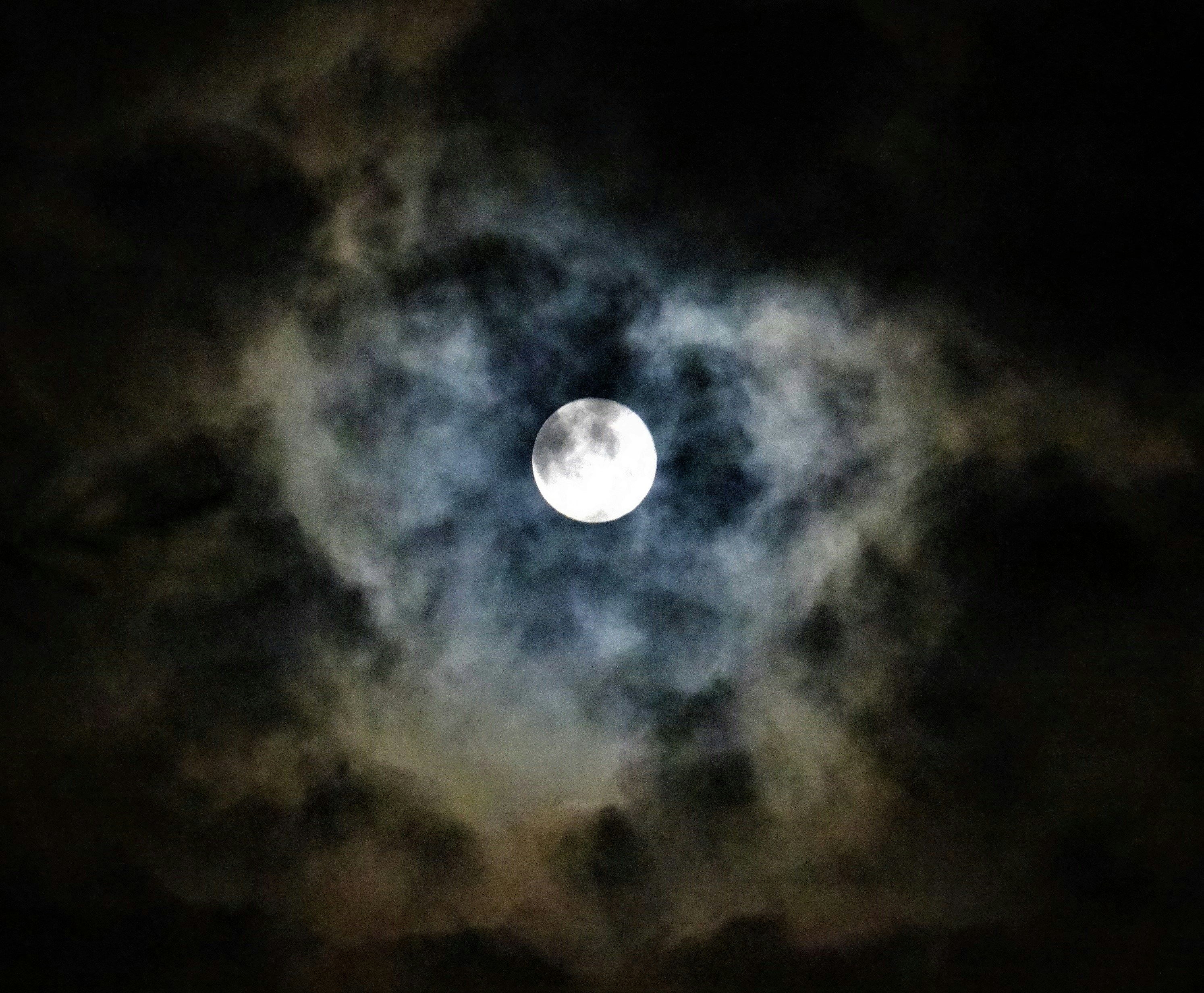 a full moon is seen through the clouds