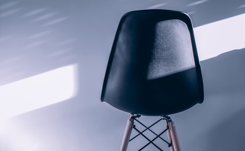 a black chair sitting on top of a wooden stand