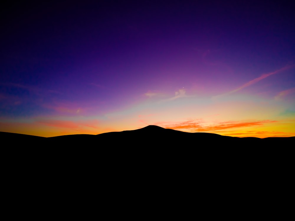 the sun is setting over a mountain range