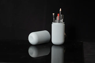 a couple of pens sitting in a cup on a table