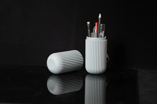 a couple of pens sitting in a cup on a table