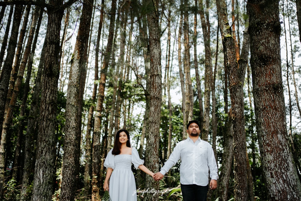 a man and a woman holding hands in the woods