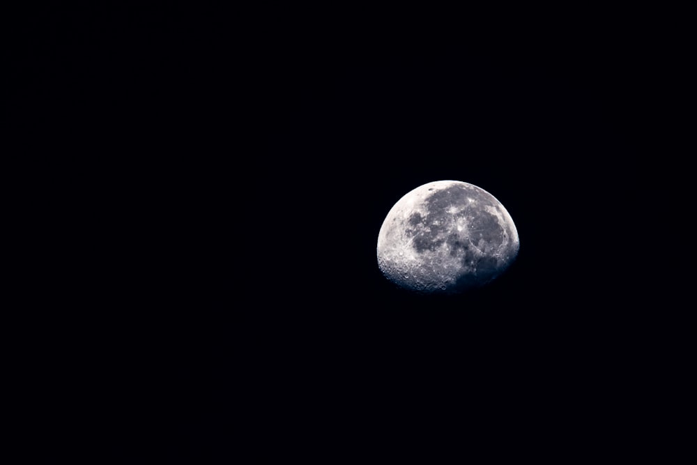 a full moon is seen in the dark sky