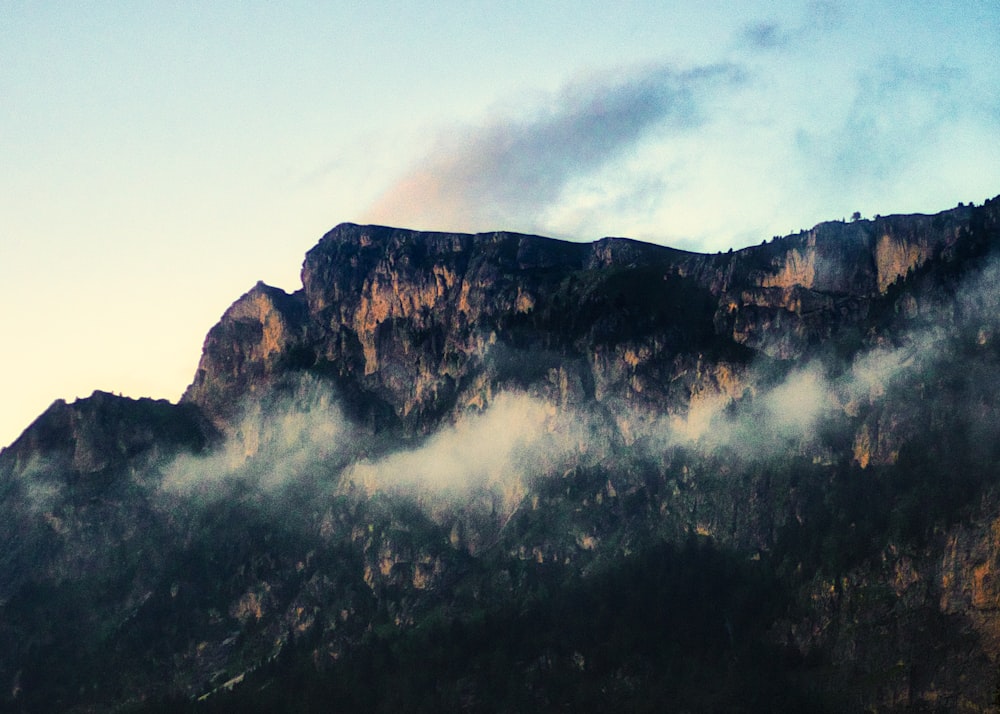 a very tall mountain with some clouds in the air