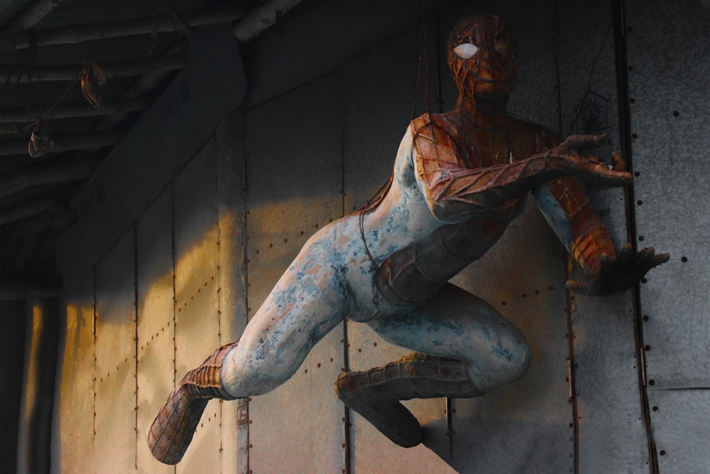 uma estátua de um homem-aranha pendurado em uma parede