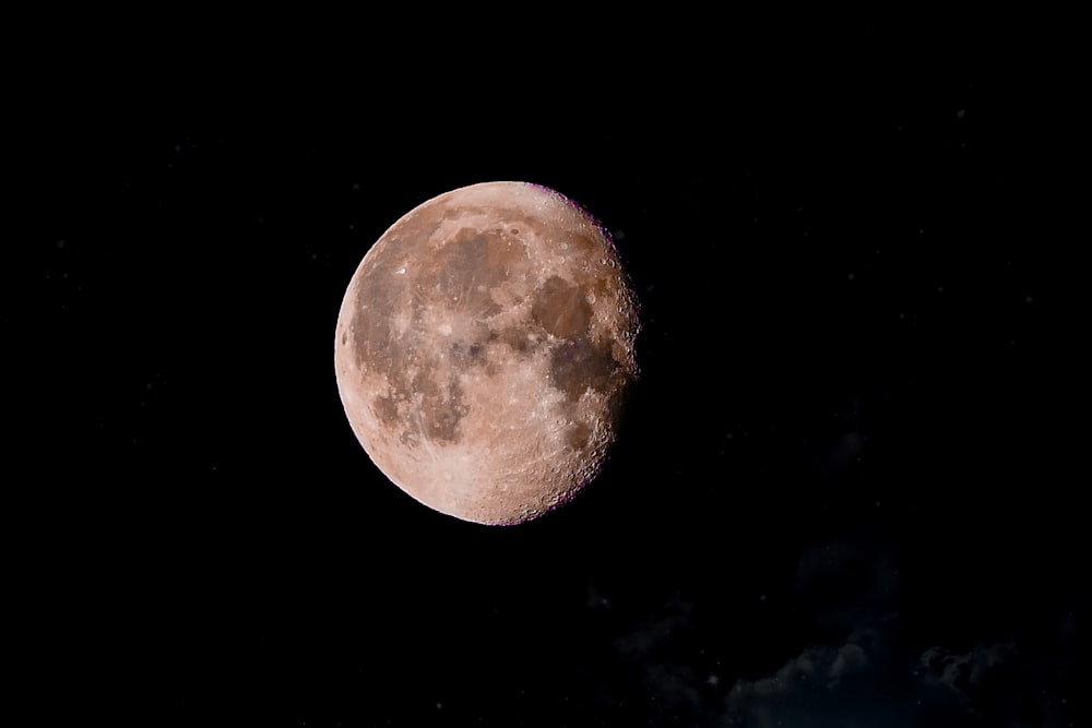 a full moon is seen in the dark sky