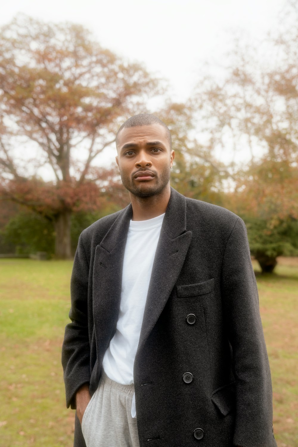 a man standing in a field wearing a jacket