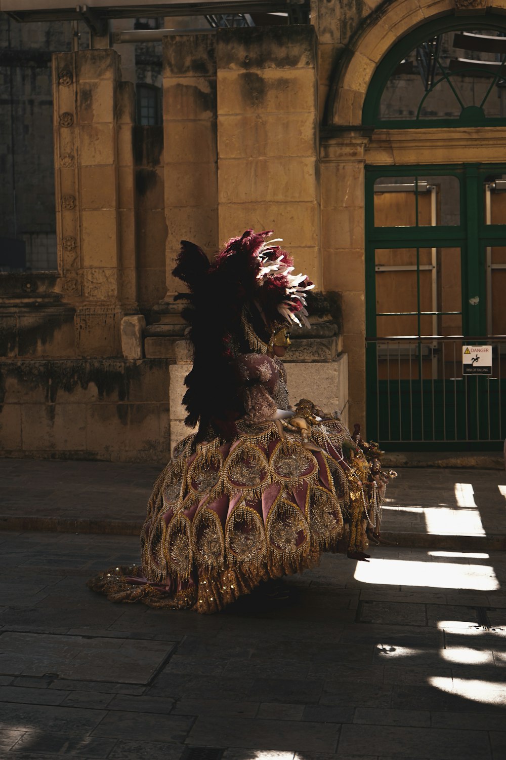 a woman in a feathered dress sitting on a sidewalk