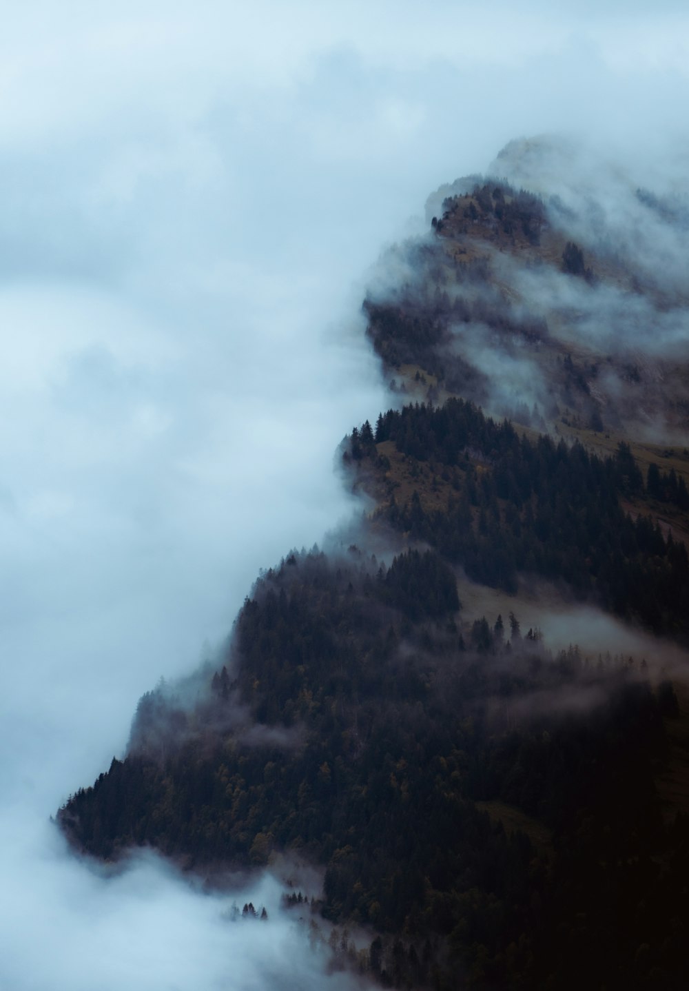 a mountain covered in fog and clouds on a cloudy day