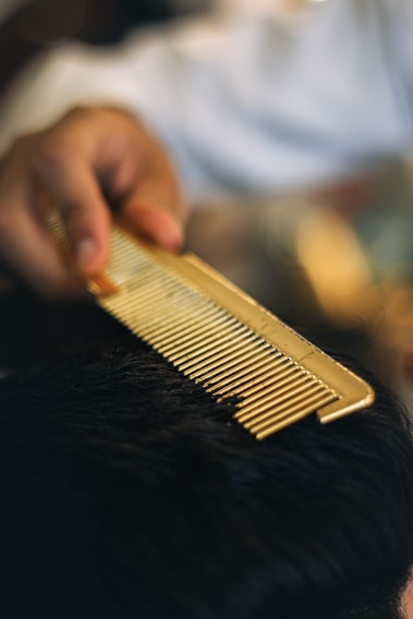 a close up of a person cutting a mans hair