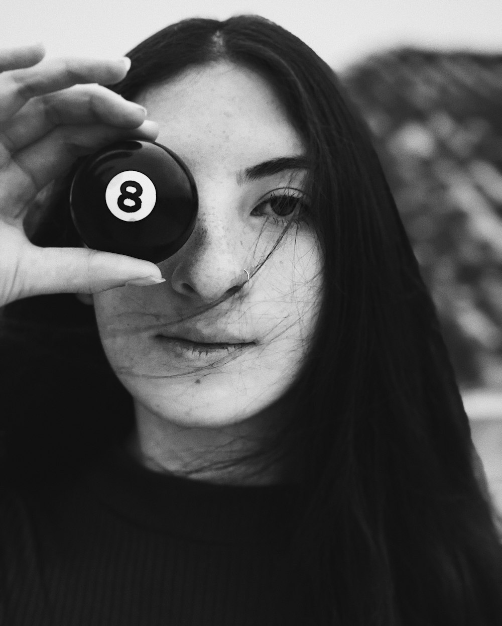 a woman holding a pool ball in front of her face