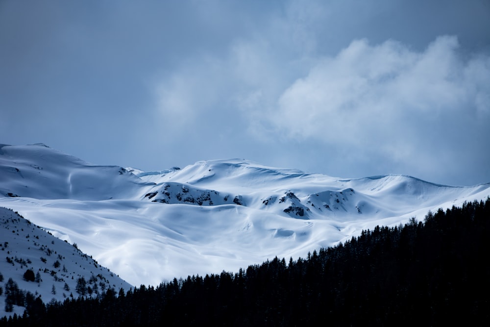 a mountain covered in snow under a cloudy sky