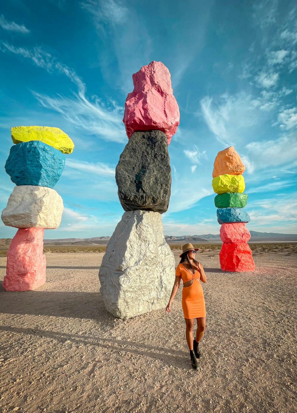 a woman in an orange dress standing in front of a rock formation
