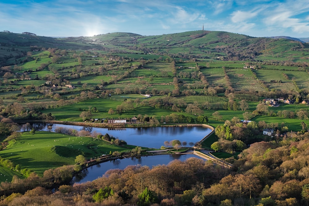 an aerial view of a lake surrounded by lush green hills