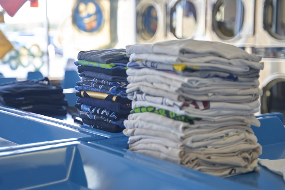 a stack of folded shirts sitting on top of a blue table