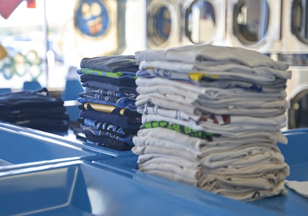 a stack of folded shirts sitting on top of a blue table